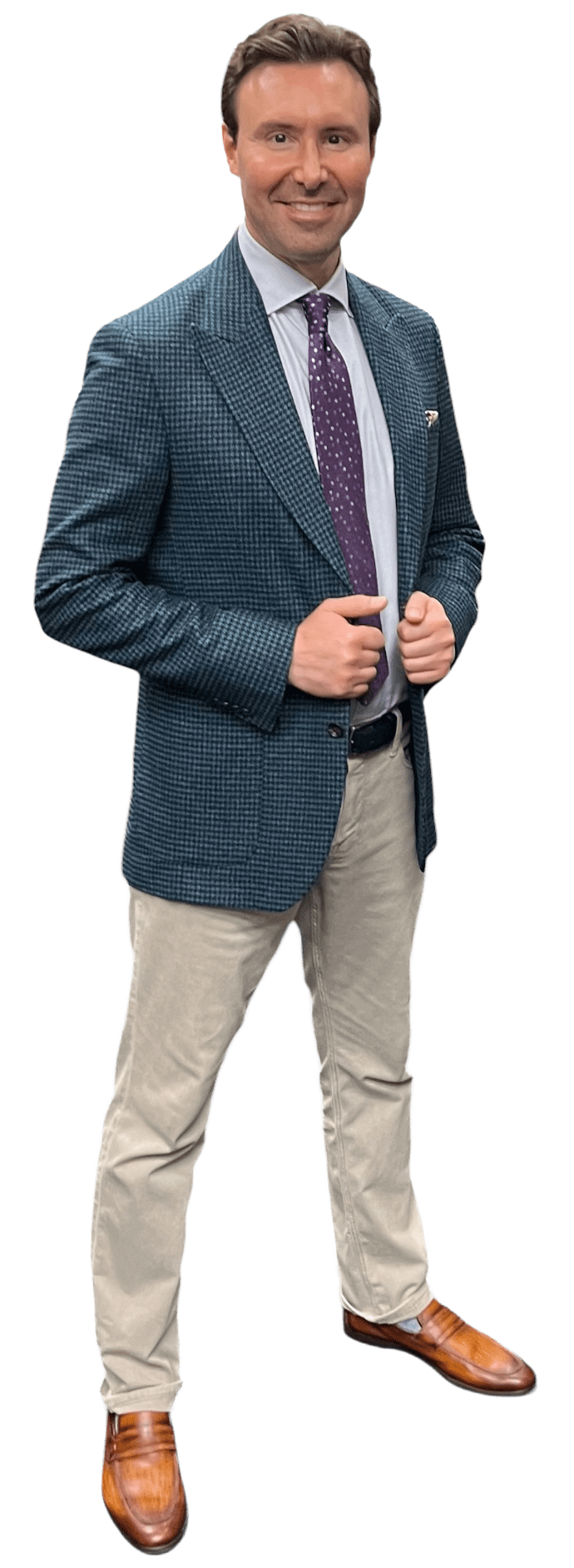 A man in a stylish blue checkered blazer and purple tie stands confidently, hands on hips