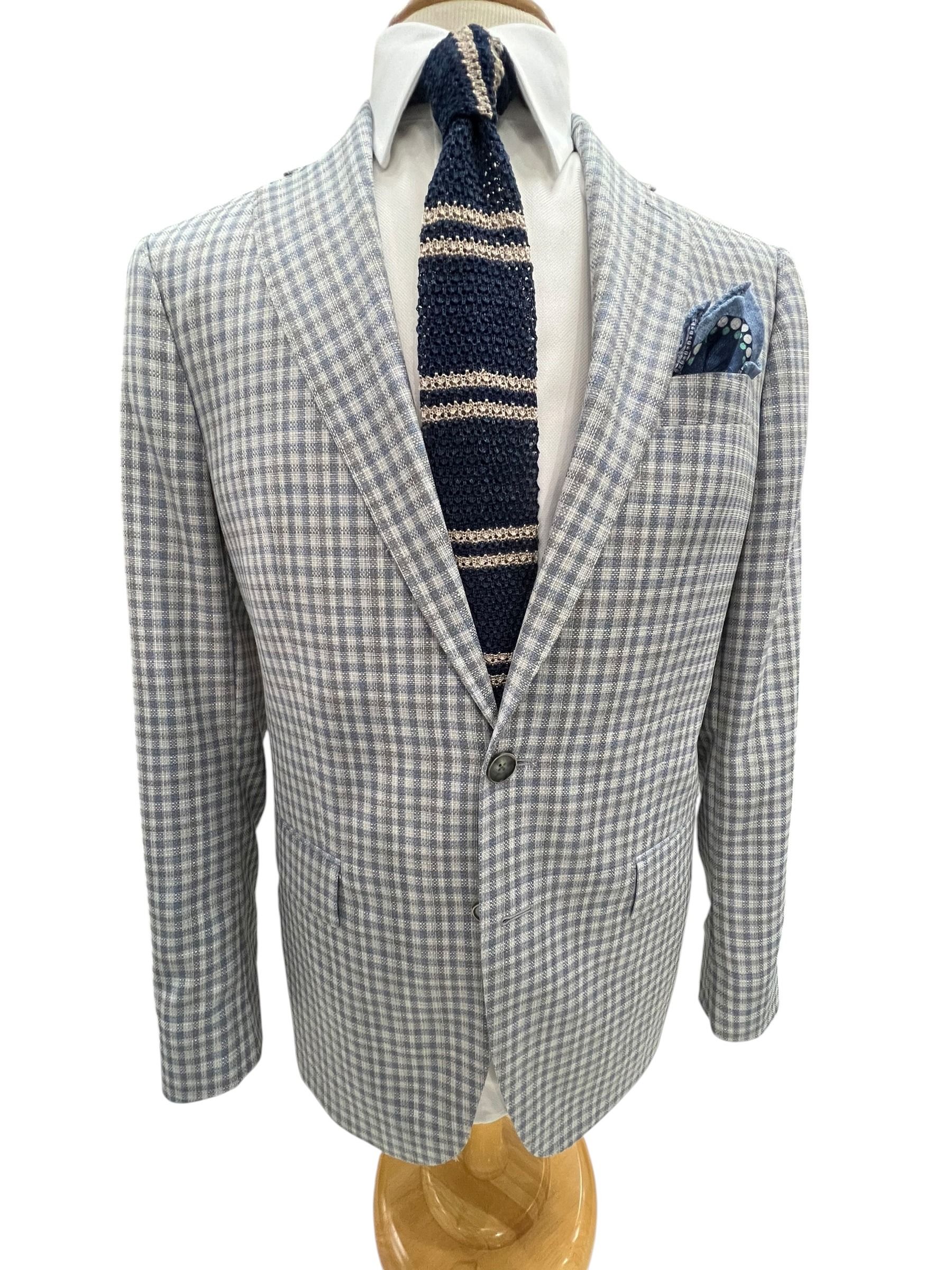Stylish gray and white checked blazer paired with a dark striped tie and a pocket square,