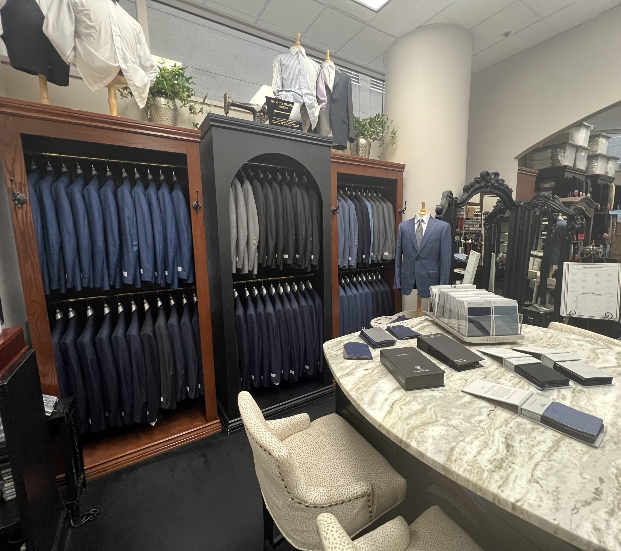 Suit display in a tailored clothing store featuring organized racks of blazers in various shades